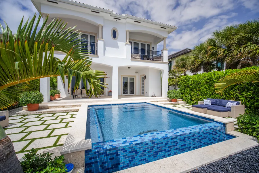 Mediterranean-style pool with blue glass tile and lush palms