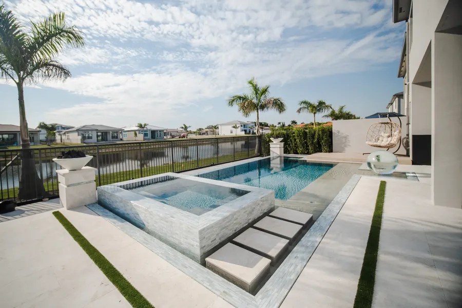 Pool and raised spa with lakefront views and lush landscaping